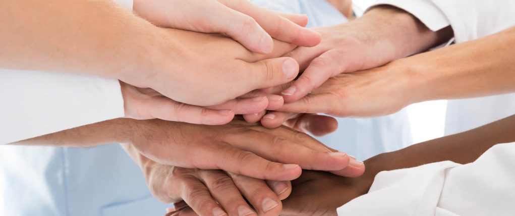 Cropped image of medical team stacking hands against white background